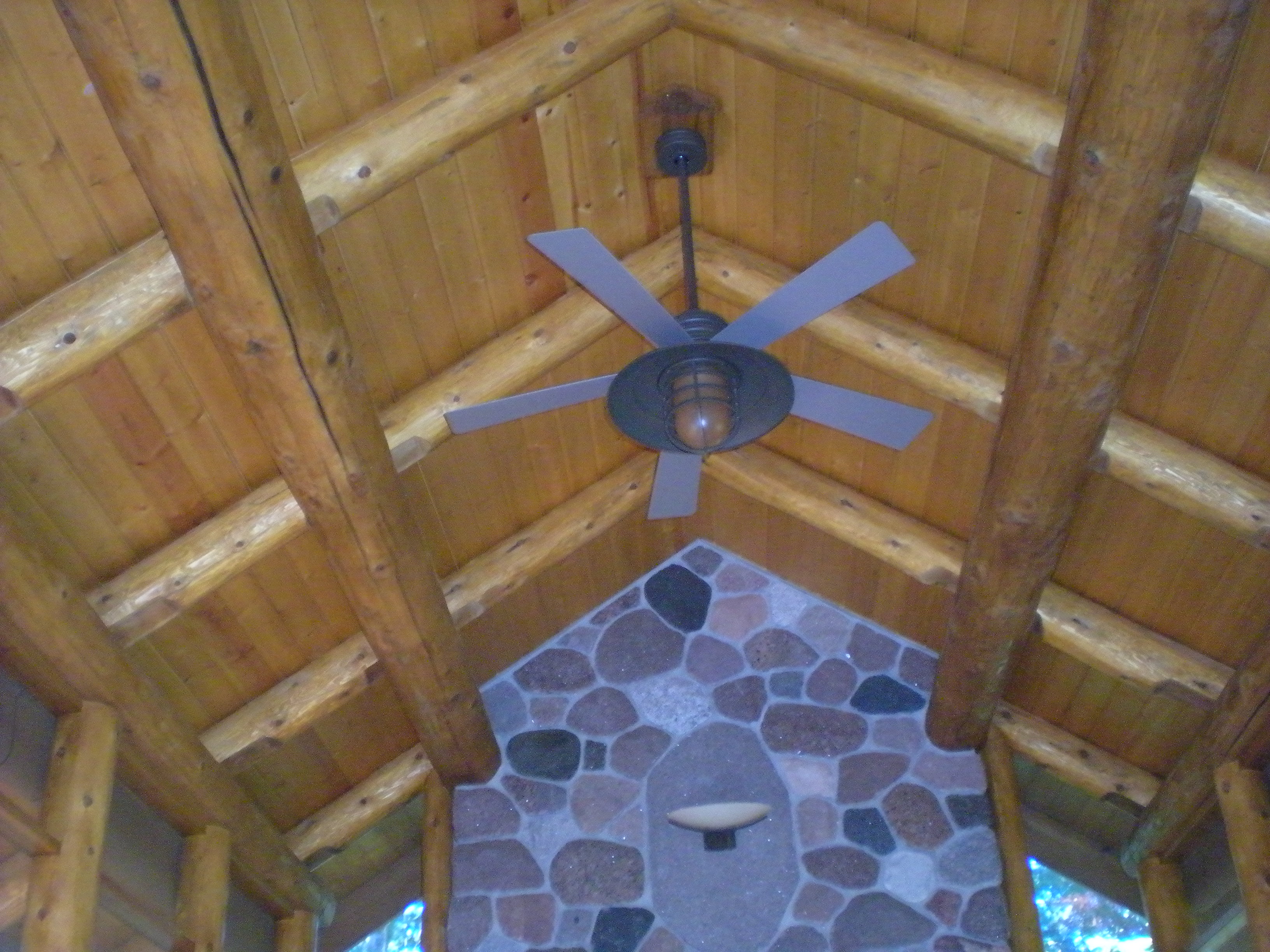 Ceiling fan against the log perlin and rafter roof