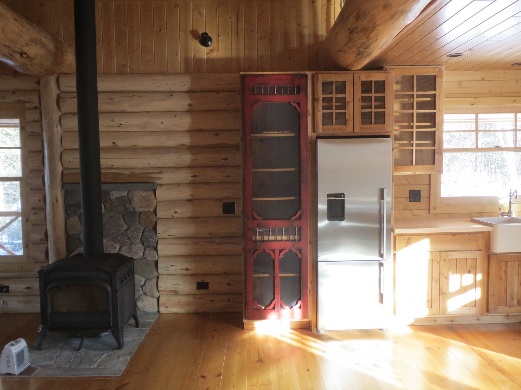 Red screen door on cabinets next to the wood stove in the living room